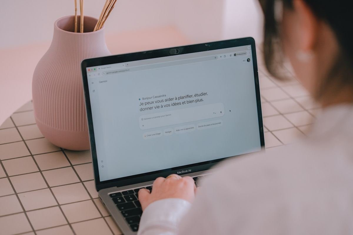 Persona escribiendo en un portátil con un asistente de inteligencia artificial en pantalla