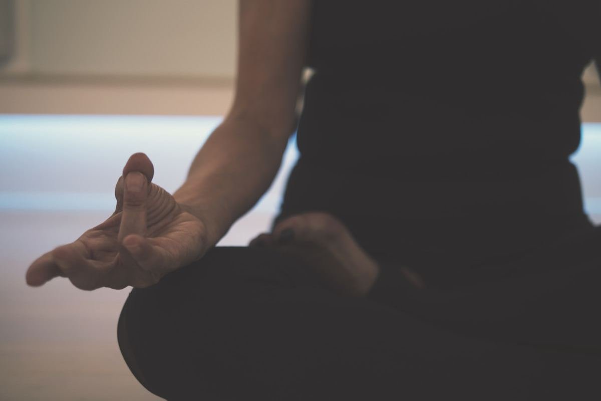 Manos en posición de meditación sobre las rodillas con luz suave